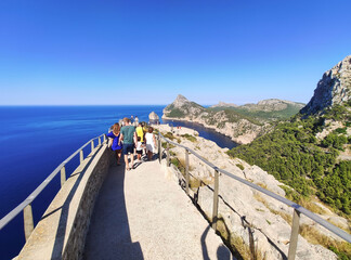 Naklejka premium Es Colomer Viewpoint, Port de Pollenca, Mallorca, Balearic Islands/Spain - 19th of August 2020: Tourists on scenic viewpoint on Formentor Peninsula near the Formentor Lighthouse looking at landscape