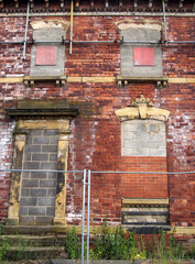 facade of an abandoned derelict old house with crumbling brick walls and blocked up windows
