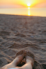 woman legs in sand close up. sunset above the sea