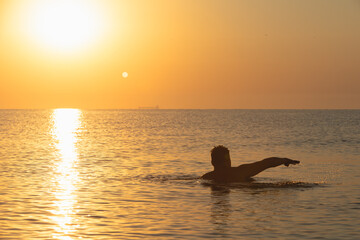 strong man swimming in sea at sunrise
