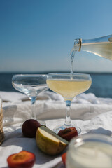 a cozy picnic in nature, on the pier. a carbonated drink is poured into a glass against the background of a blue sky. Fresh fruit