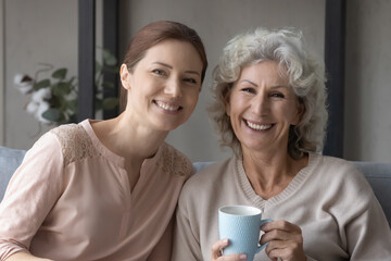 Conversation for cup of tea. Portrait of two happy women friends of diverse generations young...