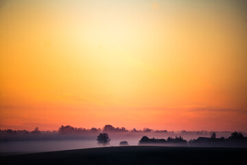 Fototapeta na wymiar A minimalist landscape of a misty sunrise in summer with a far horizon. Summertime scenery of Northern Europe.