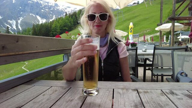 Woman drinking a draft beer on top Pradaschier park station of Churwalden town of Switzerland. Famous tourist resort for climbing activities and toboggan run in Grisons canton.