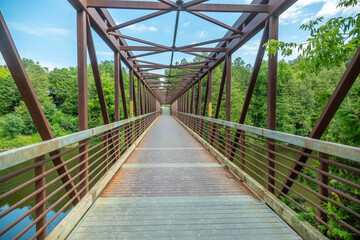 A bridge that leads into a walk path with trees.