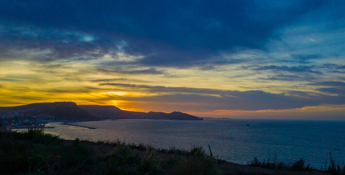 sunset above the sea, dramatic sky and sunset above the coast of Oran with moutains and jetty in the background. Tourism concept