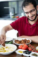 Fototapeta na wymiar Middle Eastern young man sitting and eating traditional food alone