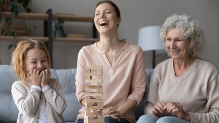 Having fun. Overjoyed old lady mother grandma engaged in funny activity with adult daughter and preteen girl grandkid. Happy family of three diverse age females play game laugh on hilarious situation