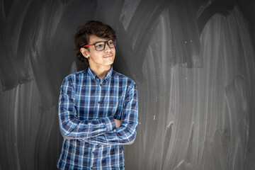 Teenage boy with glasses in front of classroom chalkboard