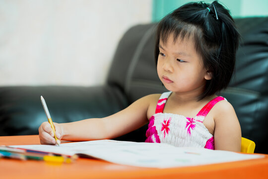 Asian child is sluggish having sleepiness while doing homework. Girl close half eyes. Cute kid aged 4-5 years old.