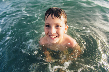 Happy child playing in the sea. Kid having fun outdoors. Summer vacation and healthy lifestyle concept. Selective focus