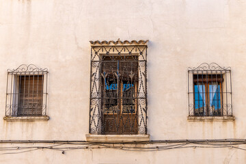 facade of an old house, with a small balcony and two windows with forged metal bars. 