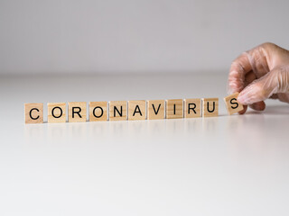 coronavirus - napis z drewnianych kostek, ręka w rękawiczce 