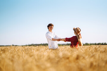 Fototapeta na wymiar Young happy couple hugging on a wheat field, on the sunset. Enjoying time together. The concept of youth, love and lifestyle.