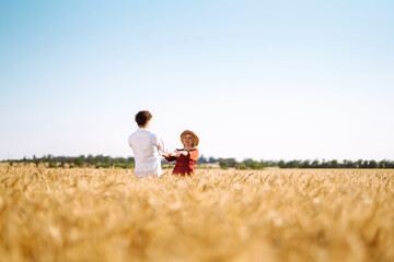 Naklejka na ściany i meble Young happy couple hugging on a wheat field, on the sunset. Enjoying time together. The concept of youth, love and lifestyle.