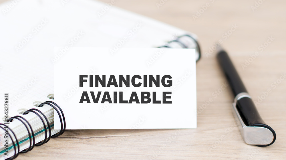 Poster financing available text on card, next to a notebook and a pen on the table. fundraising and additio