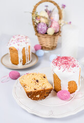 Fototapeta na wymiar Easter cake with raisins in sugar glaze. festive pastries with pink sprinkles, painted eggs, pussy willow and Easter decor on a white background. religious holiday 