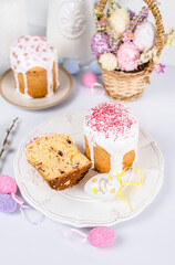 Easter cake with raisins in sugar glaze. festive pastries with pink sprinkles, painted eggs, pussy willow and Easter decor on a white background. religious holiday 