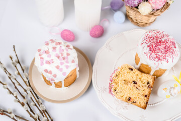 Easter cake with raisins in sugar glaze. festive pastries with pink sprinkles, painted eggs, pussy willow and Easter decor on a white background. religious holiday 