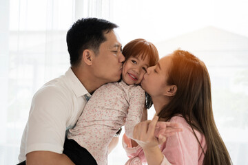 Fototapeta premium Portrait of attractive asian dad and mom kissing daughter's