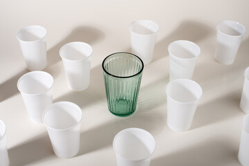 Glass among many plastic cups. Glass or plastic. Reusable versus disposable.