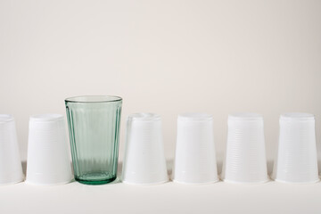 Glass and many plastic cups in a raw. Glass or plastic. Reusable versus disposable.