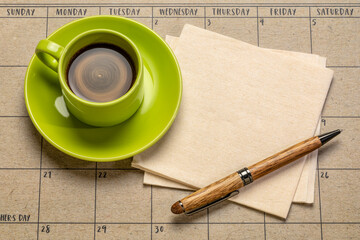 coffee, napkin and pen against desktop calendar, business still life
