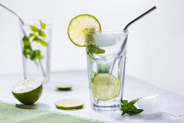 Mojito cocktails served on a bright background with lime and straw