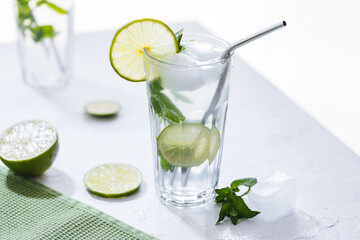 Mojito cocktails served on a bright background with lime and straw