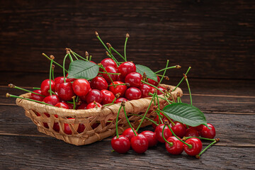 Fototapeta na wymiar Basket with a harvest of ripe cherries on wooden table