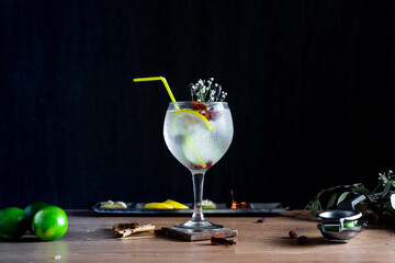 A freshly prepared gin and tonic with a plastic straw on a wooden table