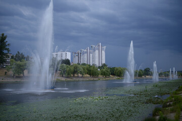 Fototapeta premium View of the Rusanovka canal, fountains working, buildings on the background and cloudy sky. Kiev, Ukraine