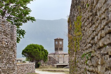 Tower clock of old fortress on blurred background of mountains in fog