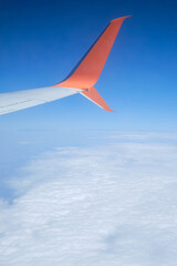Fototapeta premium Airplane wing, scenic view from the window. Higher than clouds. Beautiful cloud, blue sky. Traveling by plane, adventure. Flight over Europe. Air transport. Aviation. Holiday in other country. Poster