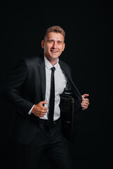 A handsome young man in a stylish black suit and smiling on a black background. Clean up, prepare.