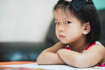 Asian girl show displeasure and strongly resist doing homework. Child sat with arms crossed and...