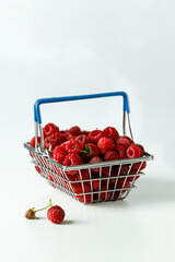 Mini grocery shopping basket with fresh raspberries on a grey background. Food photo