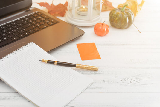autumn composition, pen, laptop, notebook, pumpkin on a white