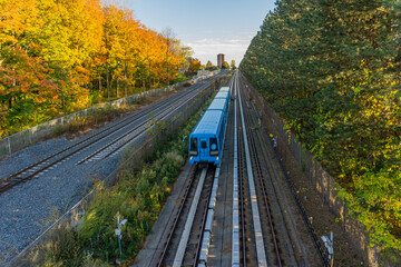 Blue rapid system train passing through the countryside forest of Scarborough, Ontario, Canada