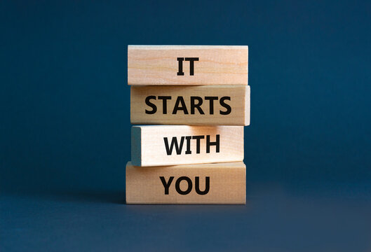 It starts with you symbol. Wooden blocks with words 'it starts with you' on beautiful grey background. Businessman hand. Business, motivational and it starts with you concept. Copy space.