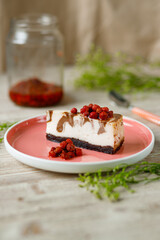 Cheesecake with chocolate flavor lies on a plate with wild strawberries on a wooden table.