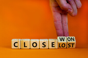 Close won or lost symbol. Businessman turns wooden cubes and changes words Close won to close lost. Beautiful orange background, copy space. Business and close won or lost concept.