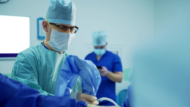Group of doctors perform an operation to a patient. Surgeons in medical uniform and masks working in the operating room.
