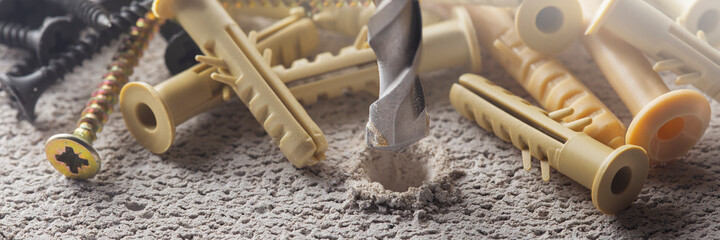 metal drill bit make holes in concrete wall with plastic dowel, wall plugs. Building work industry.