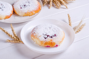 Fresh tasty bun with powdered sugar on white plate on wooden background