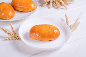 Fresh tasty patty with filling on a white plate on a wooden background