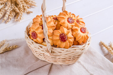 Fresh tasty shortbread cookies stuffed with jam in a wicker basket on a wooden background