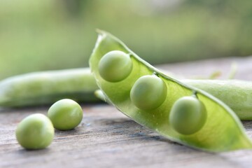 vegetables peas open pod with ripe peas on a blurred background on a wooden surface