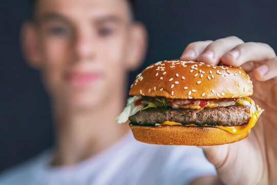 young man holds hamburger in his hands, fast food, close-up