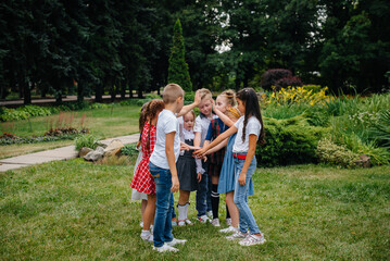 Obraz premium A group of children run around, have fun and play as a larger team in the summer in the Park. Happy childhood